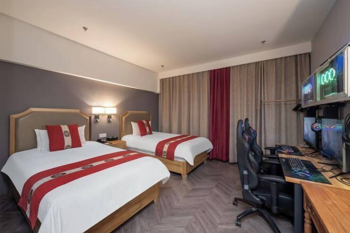 A hotel room with two beds, a desk with a computer, and a TV.