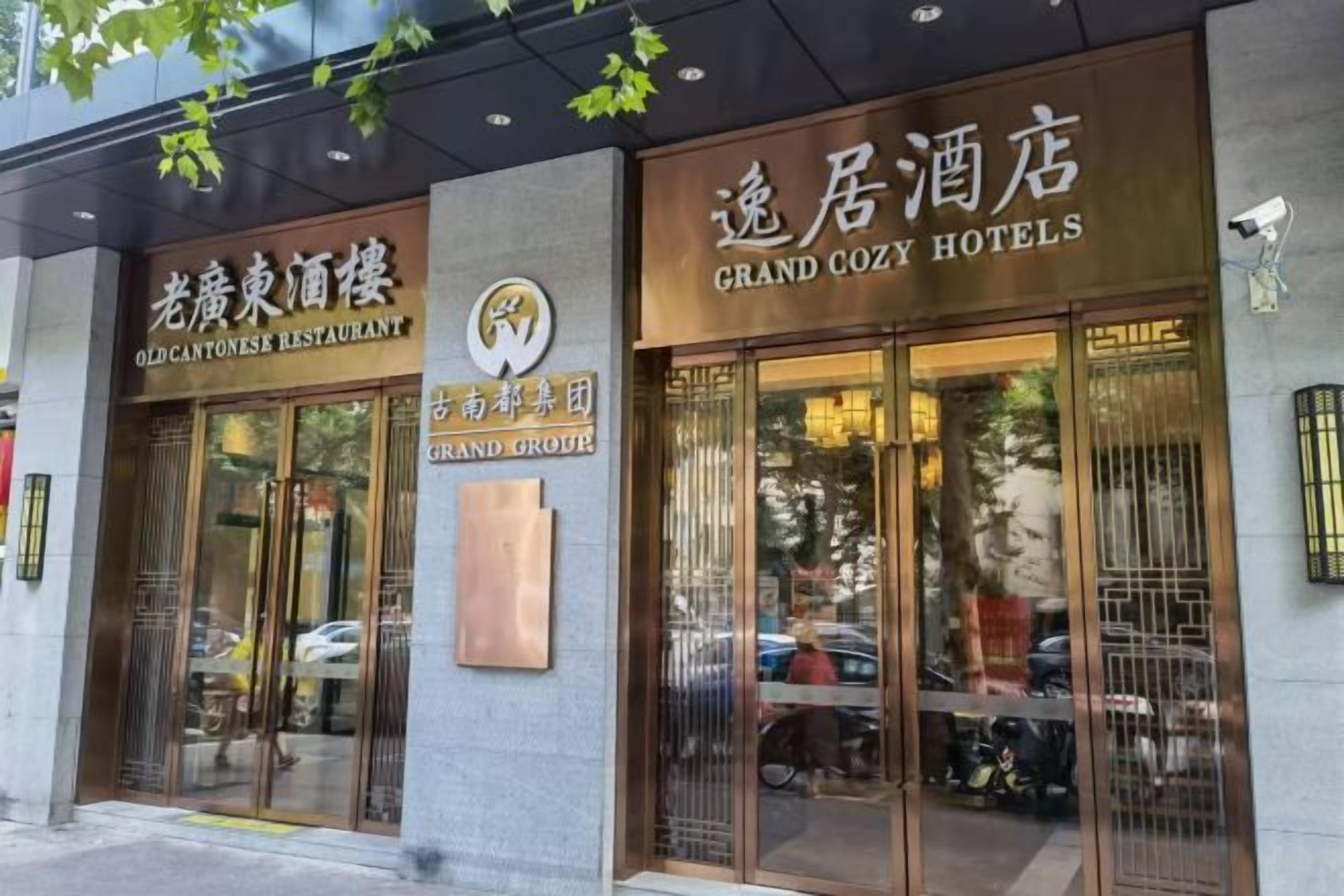 Een gebouw met twee ingangen, waarvan één 'Old Cantonese Restaurant' aangeeft en de andere 'Grand Cozy Hotels'.