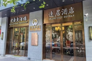 A building with two entrances, one labeled 'Old Cantonese Restaurant' and the other 'Grand Cozy Hotels.' - Grand Cozy Hotel (Nanjing University of the Arts Longjiang Subway Station Store) (Nanjing)