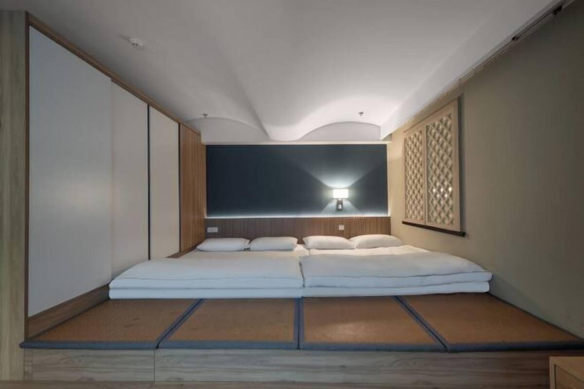 A room with a bed, a wall-mounted light, and a decorative panel.
