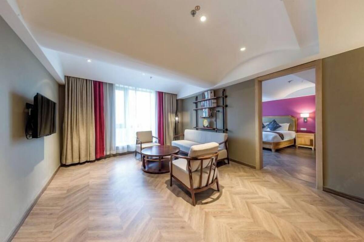 A spacious living area with a sofa, armchairs, a coffee table, and a TV mounted on the wall.