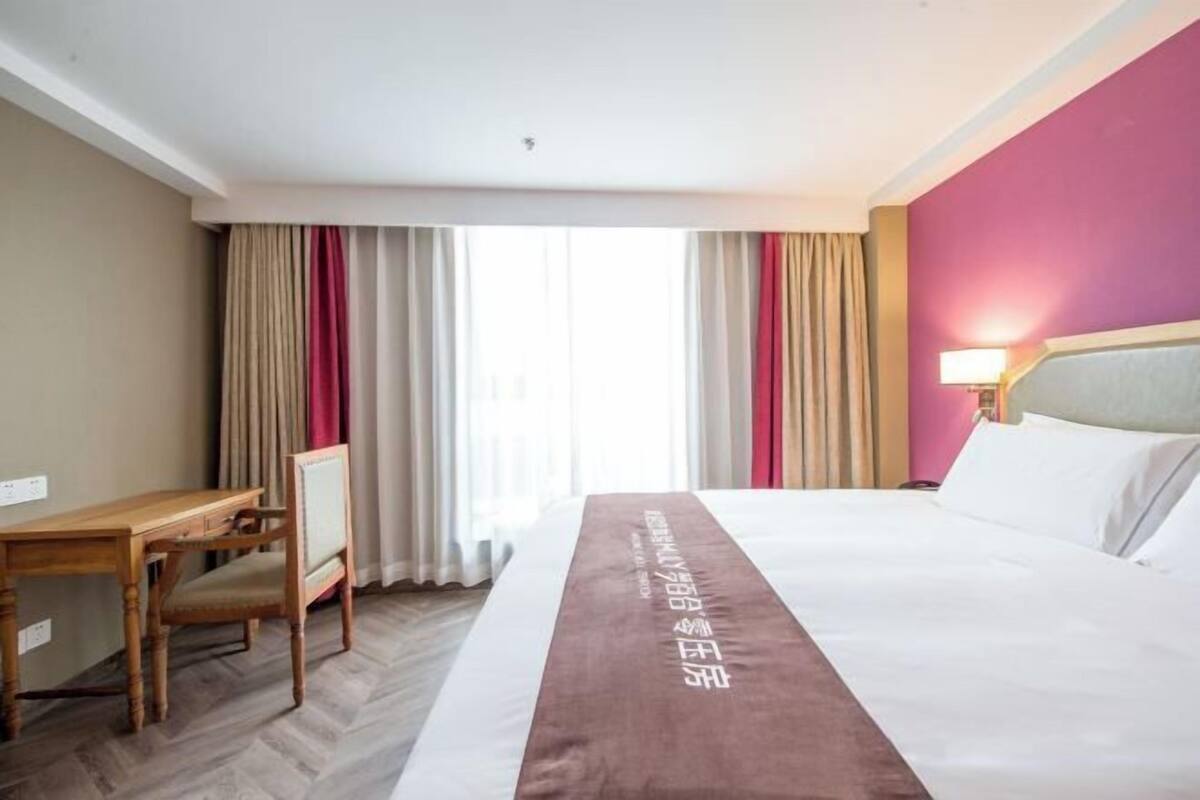 A hotel room with a bed, a desk, and a chair.