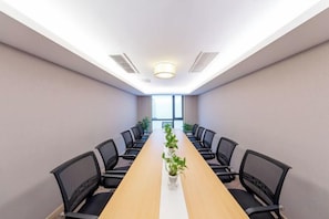 A conference room with a long table, black chairs, and a potted plant. - Grand Cozy Hotel (Nanjing University of the Arts Longjiang Subway Station Store) (Nanjing)