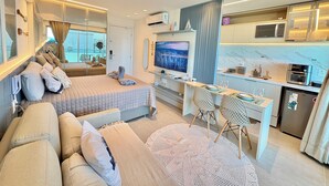 A modern hotel room with a bed, seating area, desk, and kitchenette. - RN Studio Premium 512 - Frente Mar (Maceio)