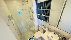 A modern bathroom with a glass-enclosed shower, a white sink, and a mirror above the sink. - RN Studio Premium 512 - Frente Mar (Maceio)
