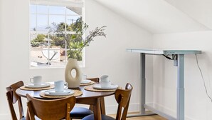 A dining area with a table set for four, a vase with flowers, and a view of the outdoors through a window. - 2Bedroom home - Marengo Estate (Alhambra)