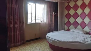 Une chambre à coucher avec un lit, une fenêtre, des rideaux et un mur décoré de motifs.