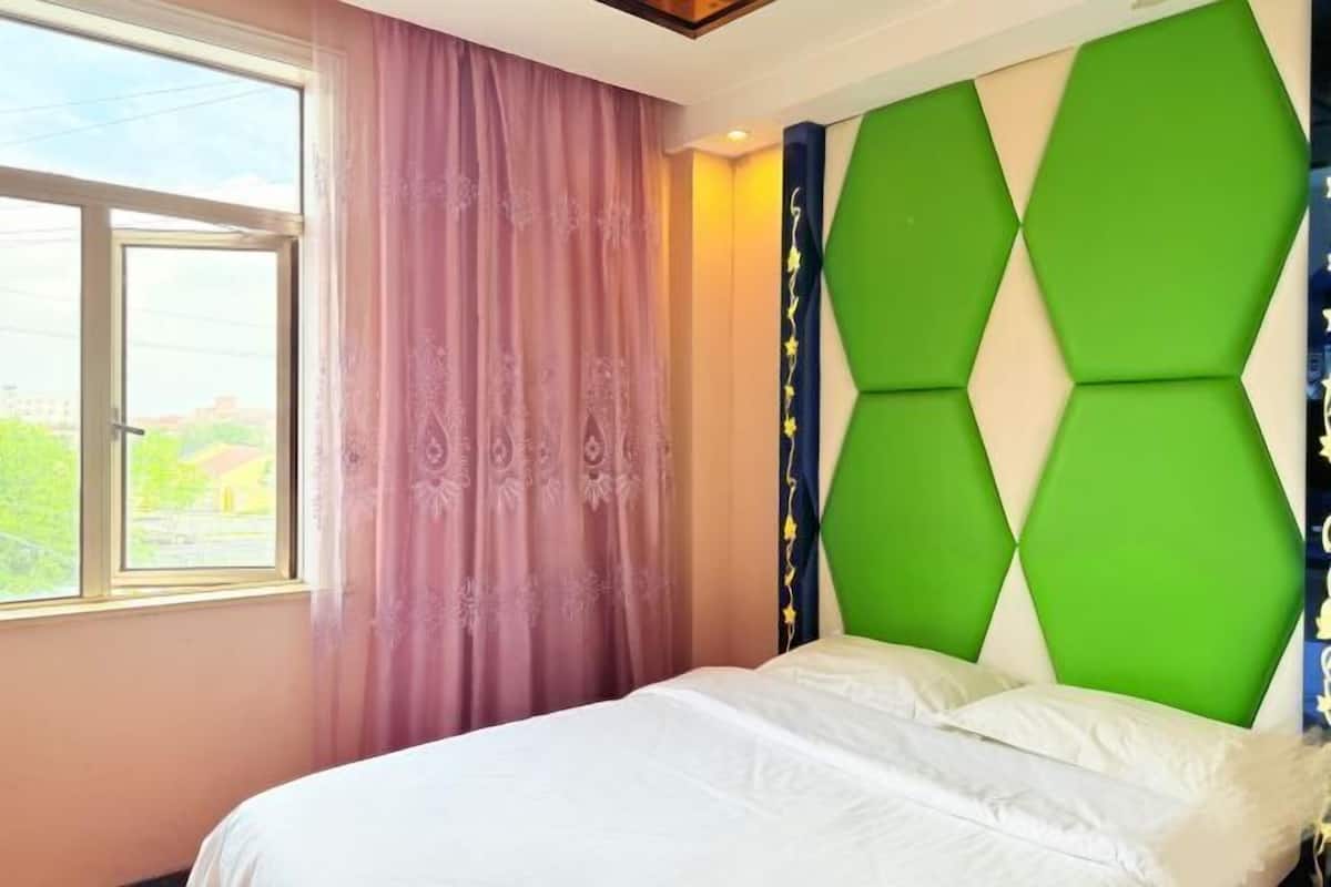 A bedroom with a bed, a window, and a wall with a geometric design.