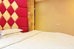A bed with white bedding, a red and yellow headboard, and a plain wall.