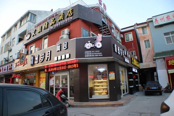 A building with multiple storefronts, including a bakery with a bicycle logo and a sign indicating a promotion from December 25, 2014, to December 25, 2015.