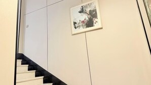 Un intérieur moderne avec un escalier, une œuvre d’art encadrée au mur et un design minimaliste.