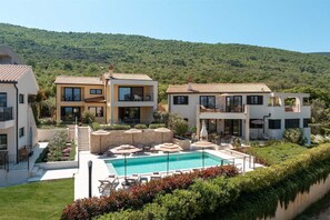 A modern villa with a swimming pool, outdoor seating, and a view of a green hillside. - Casa Andrea a sea view retreat in peaceful village (Drenje)