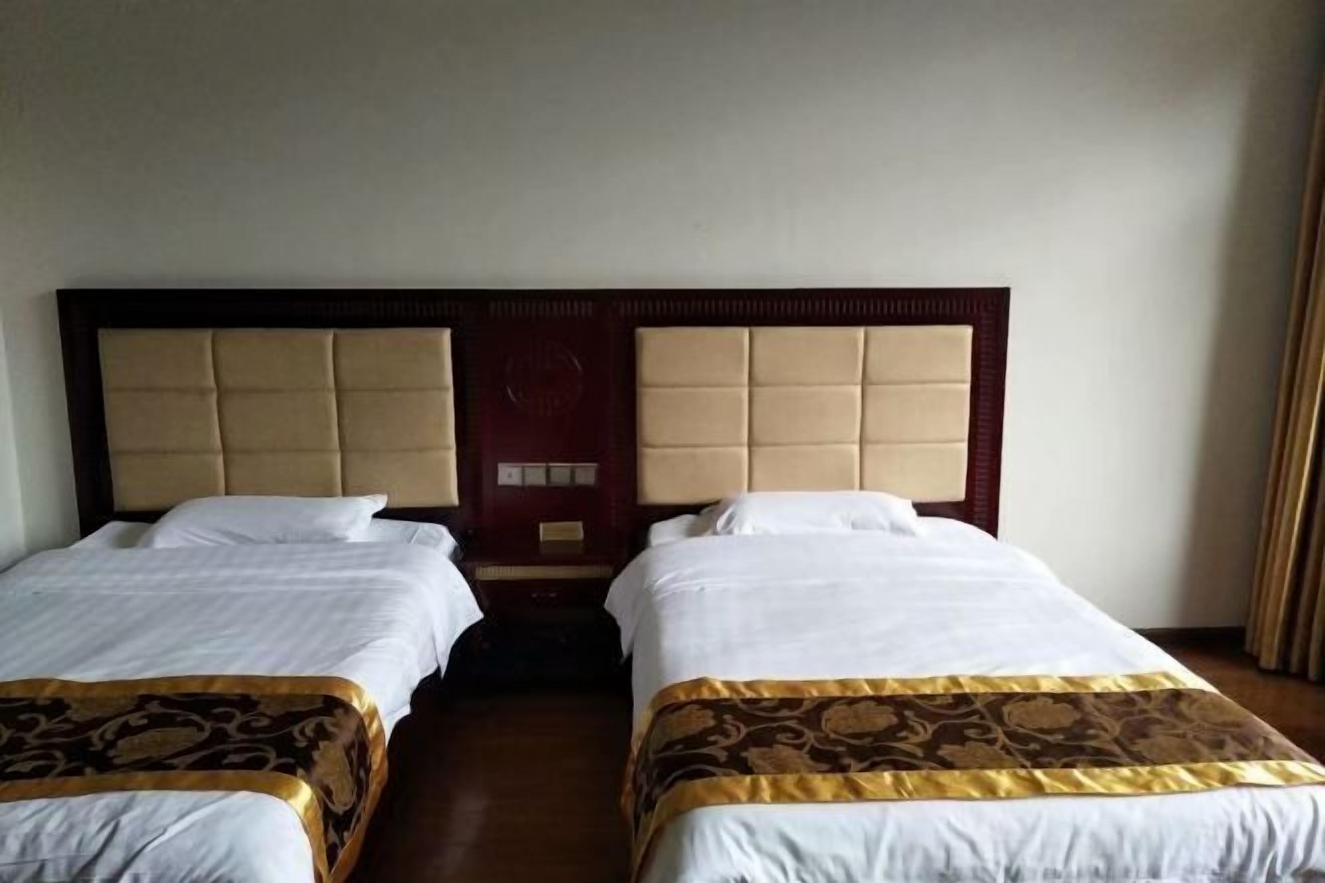 Een hotelkamer met twee bedden, elk met een hoofdbord en een decoratieve spreidek.