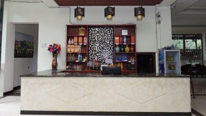 A reception area with a marble counter, decorative wall panels, and shelves with various items. - Xiushan Hotel (Emeishan City)