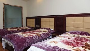 A hotel room with two beds, each with a floral bedspread, a wooden headboard, and a large window. - Xiushan Hotel (Emeishan City)
