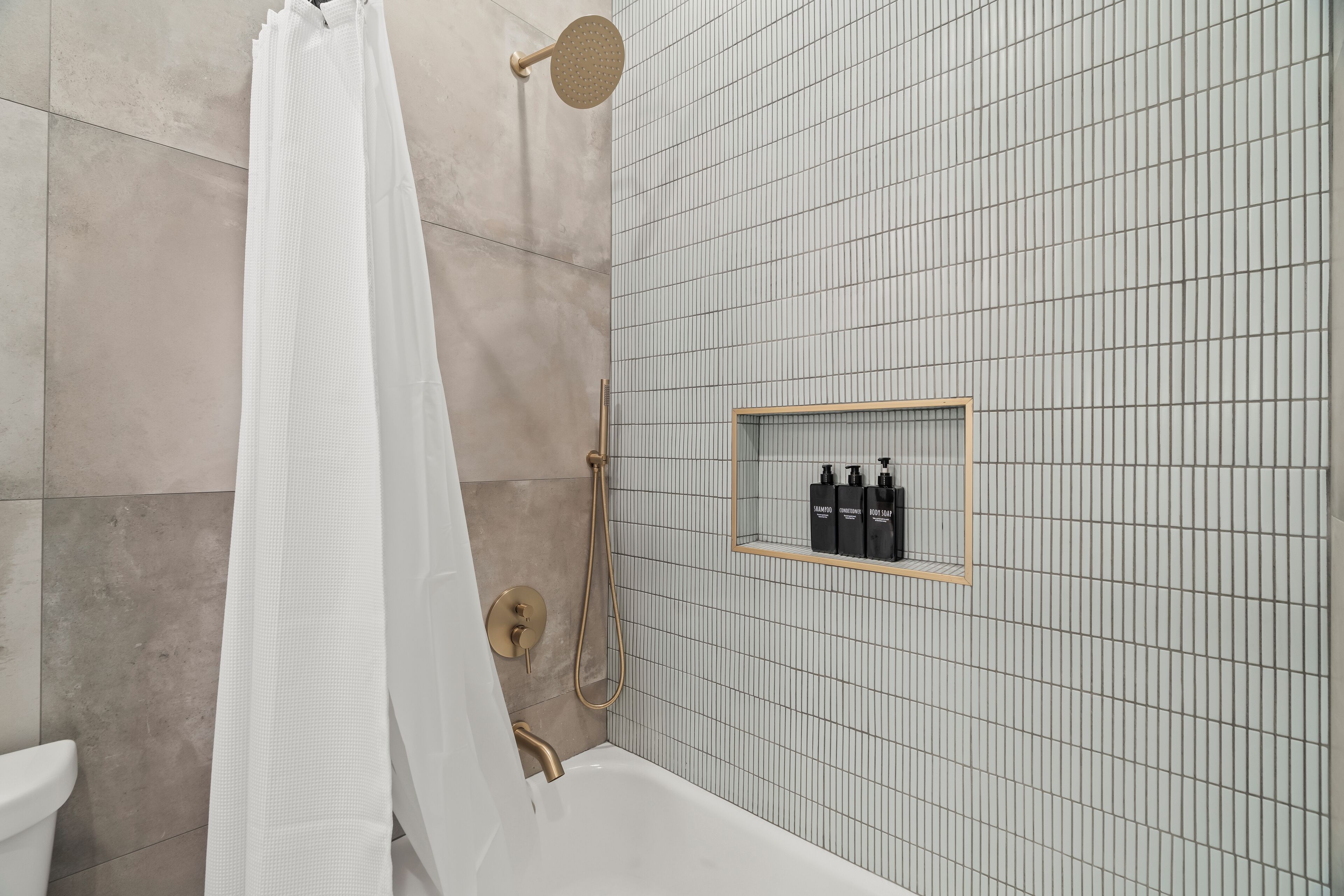 A modern bathroom with a bathtub, shower, and a shelf with toiletries.