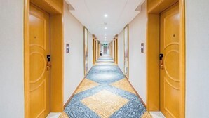 Un pasillo de hotel con puertas de madera, alfombra estampada y una larga extensión.