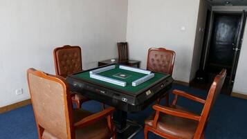 Una habitación con mesa de billar, cuatro sillas de madera y una puerta al fondo.