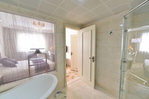 A bathroom with a bathtub, a glass shower enclosure, and a door leading to another room. - Jingbin Hotel (Beijing)