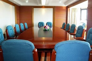 Ein Konferenzraum mit einem großen ovalen Tisch, blauen Stühlen und einer floralen Tischdekoration.