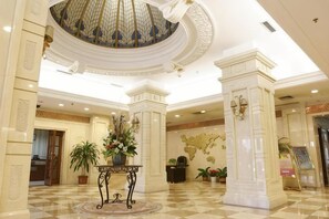 A lobby with a checkered floor, a central column, a decorative ceiling, and a reception desk. - Jingbin Hotel (Beijing)