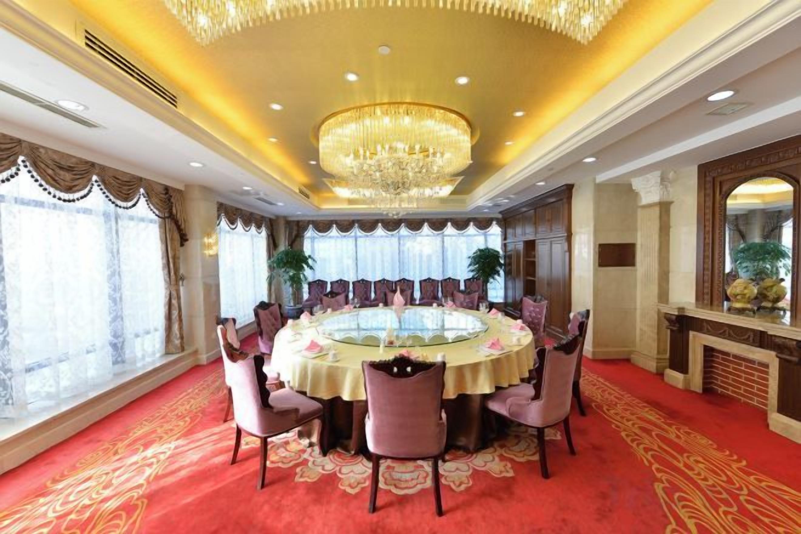 A formal dining room with a round table, chairs, and a chandelier.