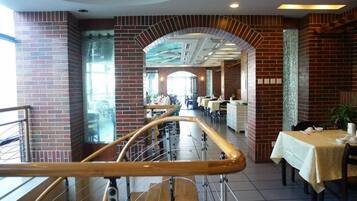 A restaurant with brick walls, a wooden railing, and tables with white tablecloths.