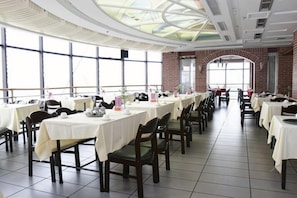 A dining hall with long tables, chairs, and a high ceiling with skylights.