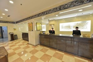 A reception area with a checkered floor, a reception desk, and a large wall-mounted artwork.