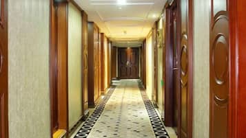 Un pasillo de hotel con puertas de madera, suelo estampado e iluminación en el techo.