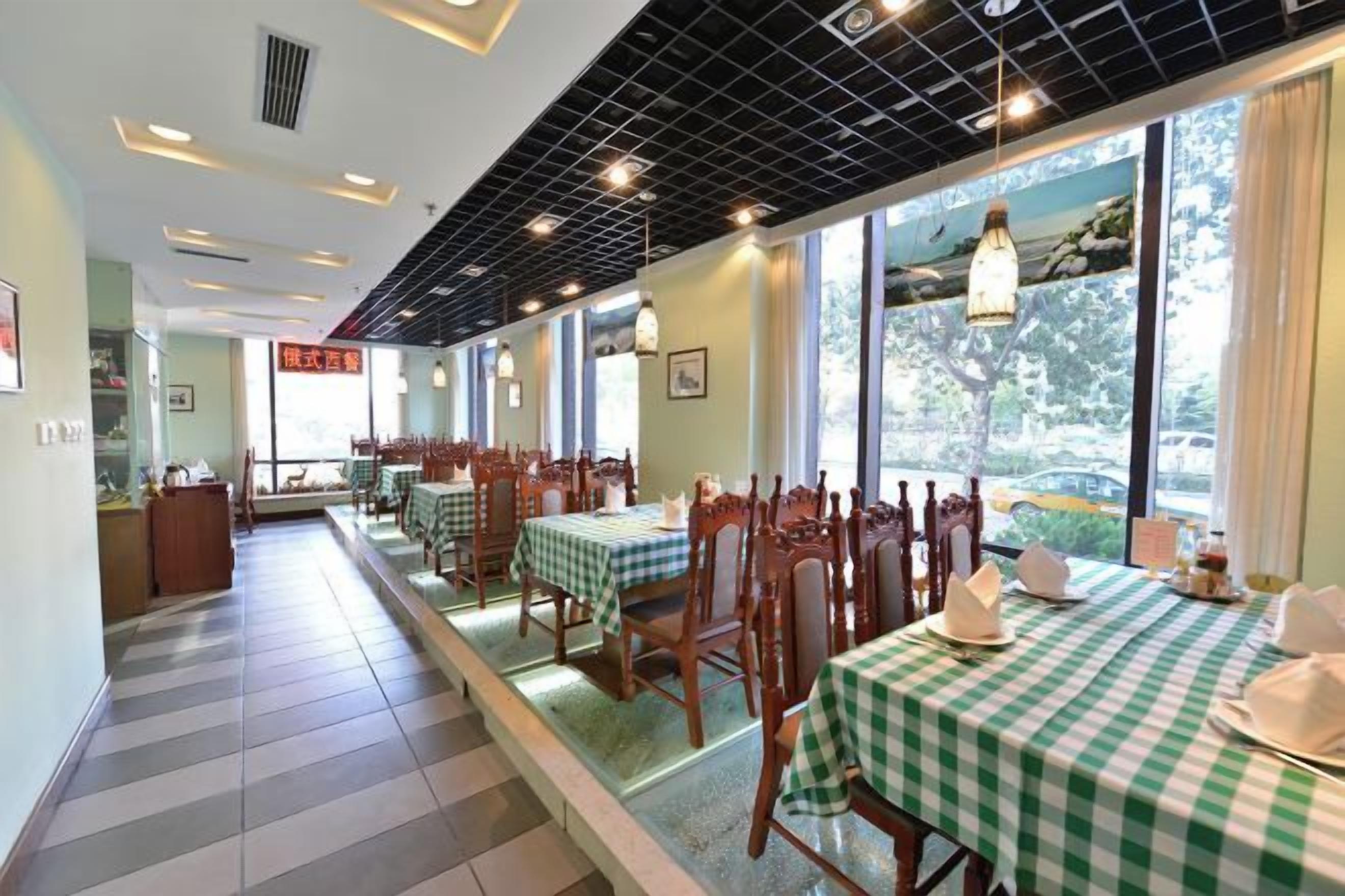 Un restaurante con manteles a cuadros, sillas de madera y grandes ventanales.