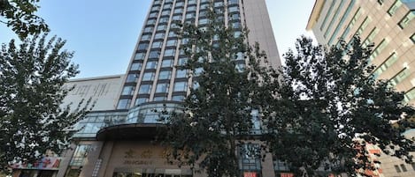 Un edificio moderno de varios pisos, con una entrada destacada que incluye puertas de vidrio y un cartel.