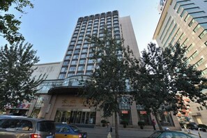A multi-story building with a modern design, featuring a prominent entrance with glass doors and a sign. - Jingbin Hotel (Beijing)