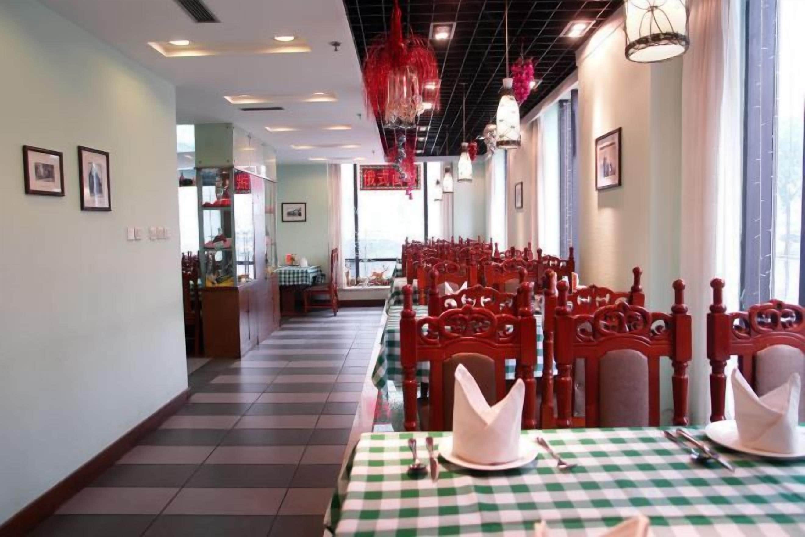 Un restaurante con mantel a cuadros, sillas rojas y suelo de baldosas.