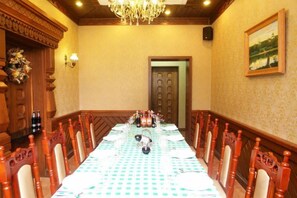 A conference room with a long table, chairs, a chandelier, a door, and a painting on the wall. - Jingbin Hotel (Beijing)