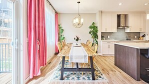 Una cocina moderna con comedor, mesa de madera y vistas al exterior.