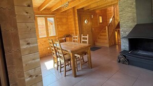 A wooden interior with a dining area, fireplace, and a staircase leading to an upper level. - Chalet for 9 people. Skiing, Hiking, and Nature - Haut-Jura (Prémanon)