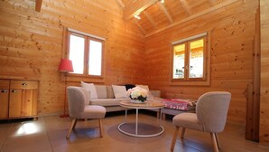 A cozy log cabin room with a sofa, two armchairs, a small round table, and a cabinet. - Chalet for 9 people. Skiing, Hiking, and Nature - Haut-Jura (Prémanon)