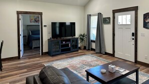 A living room with a flat-screen TV, dark wood flooring, a leather sofa, a coffee table, and a patterned rug. - Rayburn Blue•Close to Ramp•New Home•Large Driveway for Multiple Trucks and Boats (Zavalla)