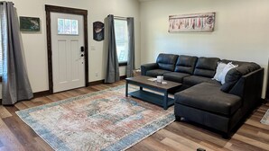 A living room with a dark leather sofa, a coffee table, and a patterned rug. - Rayburn Blue•Close to Ramp•New Home•Large Driveway for Multiple Trucks and Boats (Zavalla)