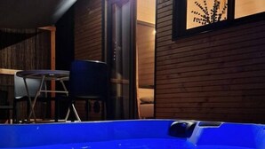 Un jacuzzi en una cabaña de madera con una mesa y sillas afuera.