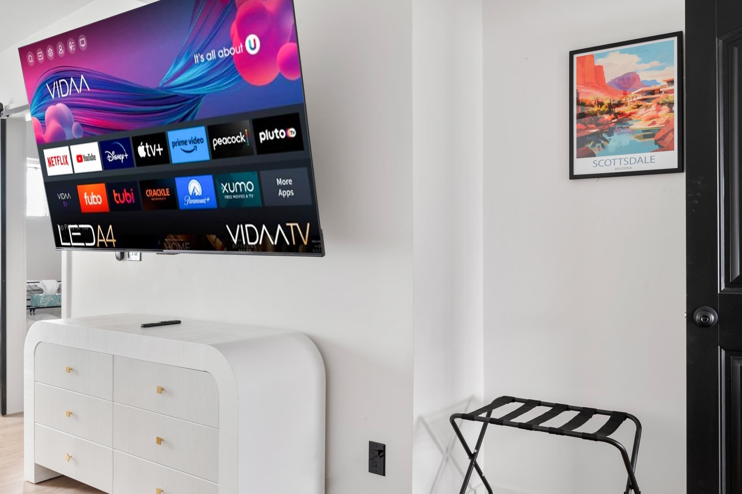 A modern living room with a mounted flat-screen TV displaying various streaming services.