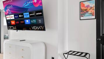 A modern living room with a mounted flat-screen TV displaying various streaming services.