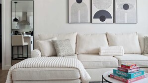 A living room with a sofa, ottoman, and a coffee table with board games.