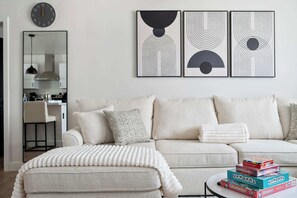 A living room with a sofa, ottoman, and a coffee table with board games.
