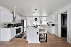 A modern kitchen with white cabinetry, a central island, and a black pendant light.