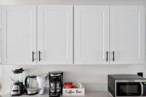 A kitchen with white cabinets, a blender, a coffee maker, a box labeled 'Coffee Bar', and a microwave. - Luxe Home 4B3B with Heated Pool/Jacuzzi & Parking (Scottsdale)