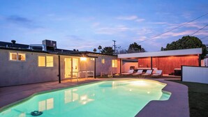 A residential property with a swimming pool, outdoor seating area, and a covered patio.