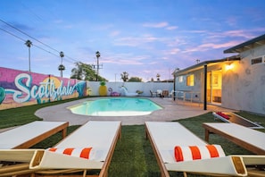 A backyard with a swimming pool, lounge chairs, and a mural on the wall. - Luxe Home 4B3B with Heated Pool/Jacuzzi & Parking (Scottsdale)