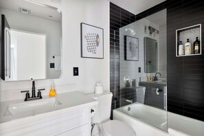 A modern bathroom with a white vanity, a large mirror, a toilet, and a glass-enclosed shower area. - Luxe Home 4B3B with Heated Pool/Jacuzzi & Parking (Scottsdale)